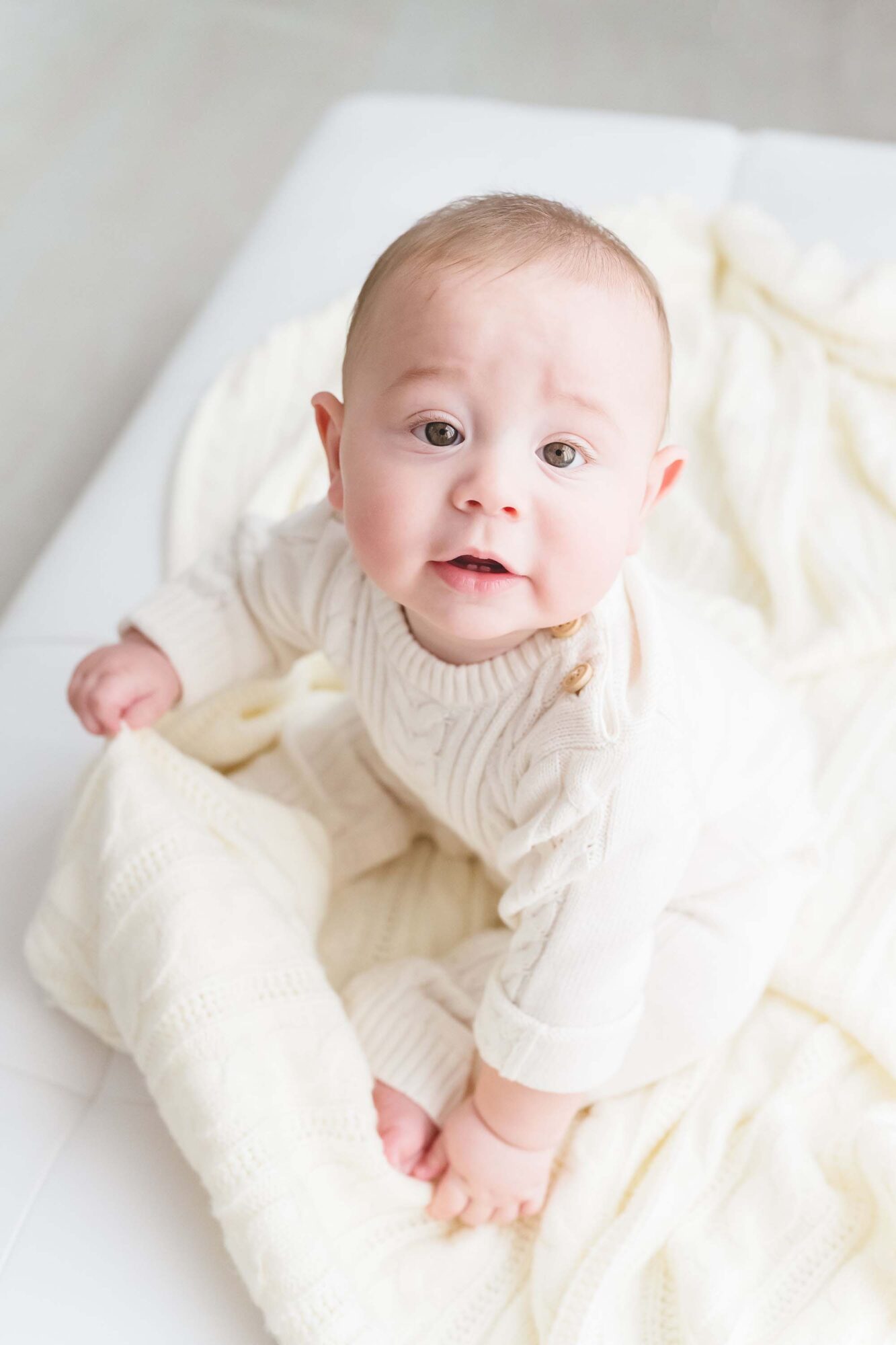 Reaj Roberts Photography Scottsdale baby photographer infant sitting up wearing a cute cable knit romper
