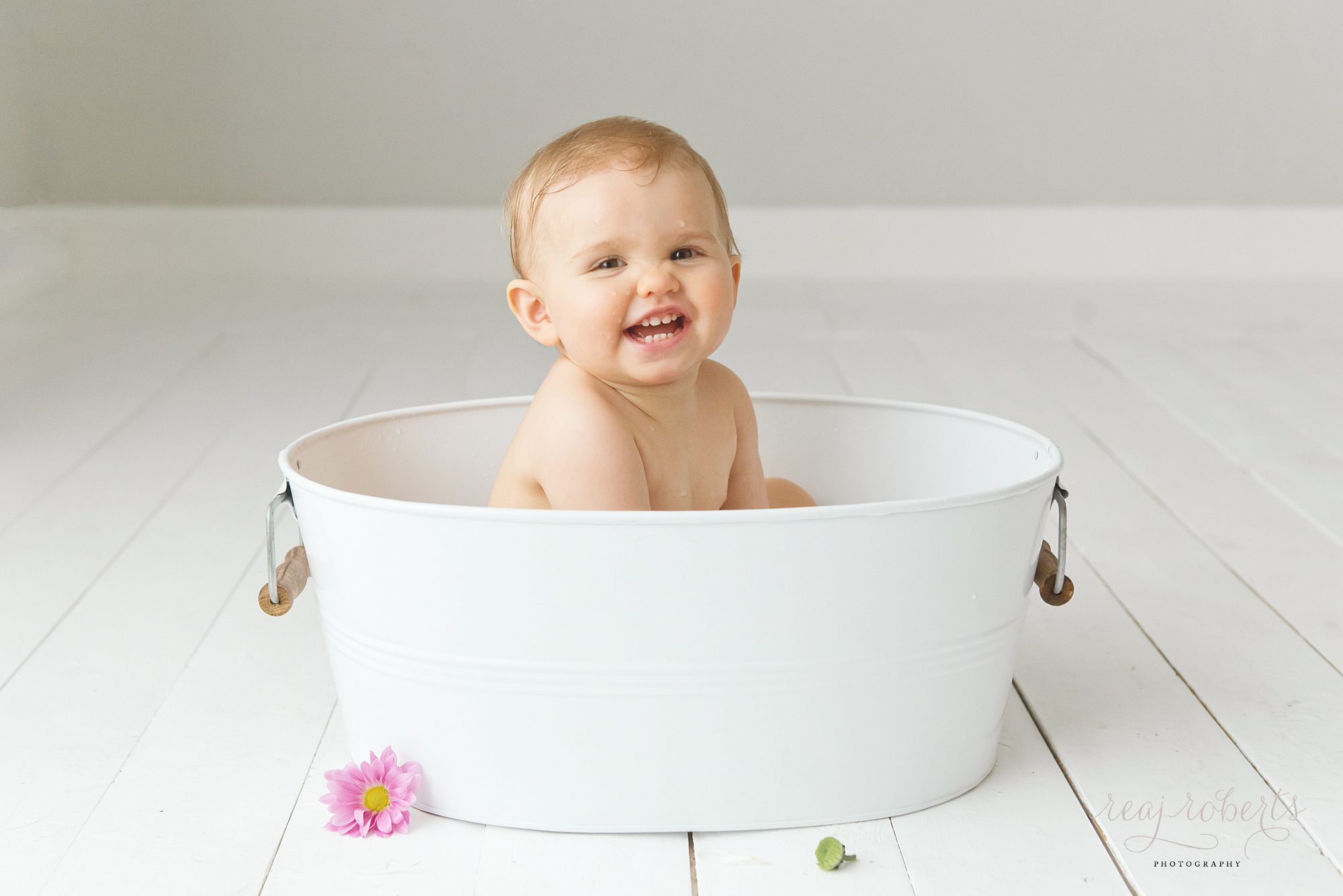 baby girl smiling in large white bucket | Reaj Roberts Photography
