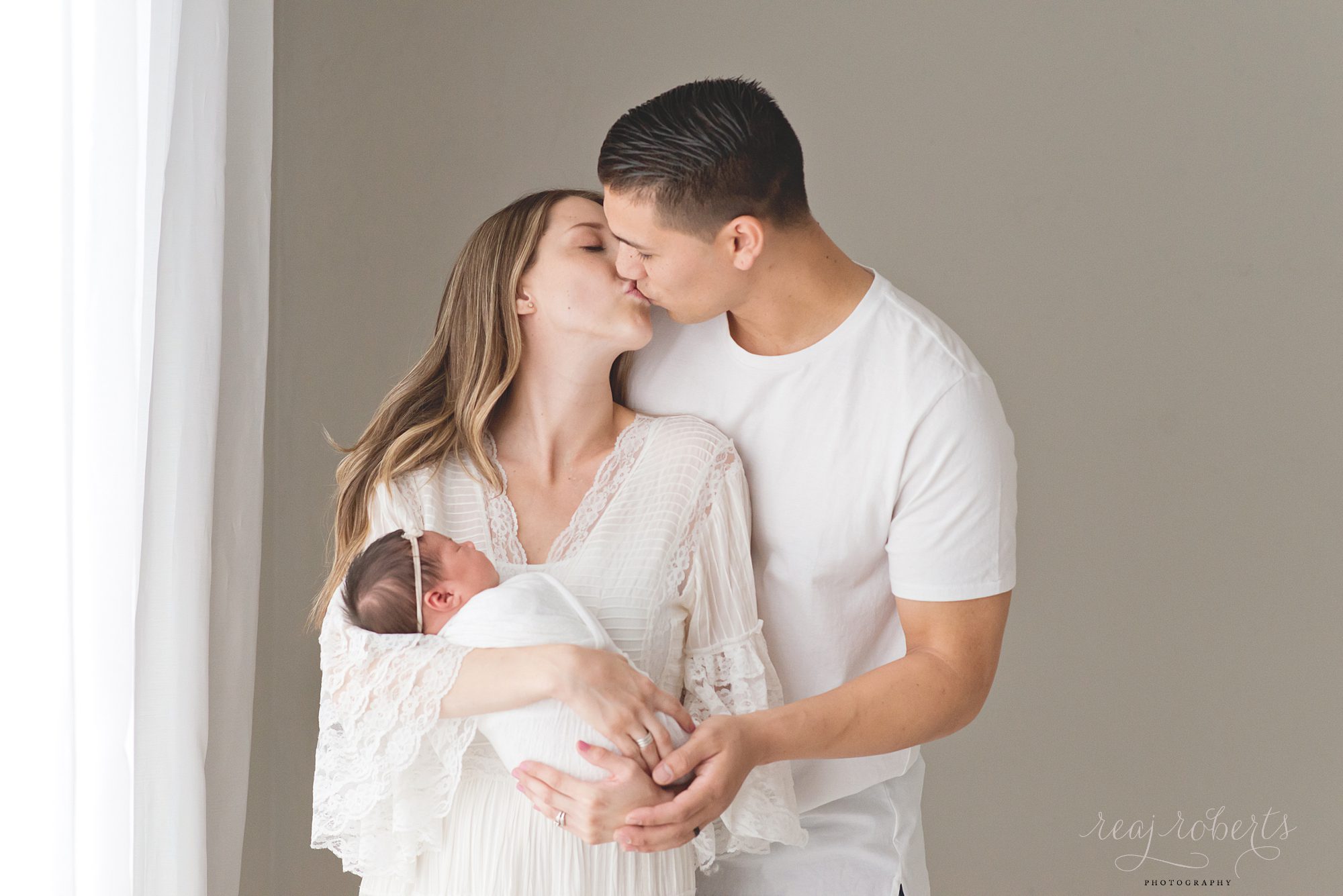 Phoenix Baby Photographer | Reaj Roberts Photography | new parents kissing holding newborn pose