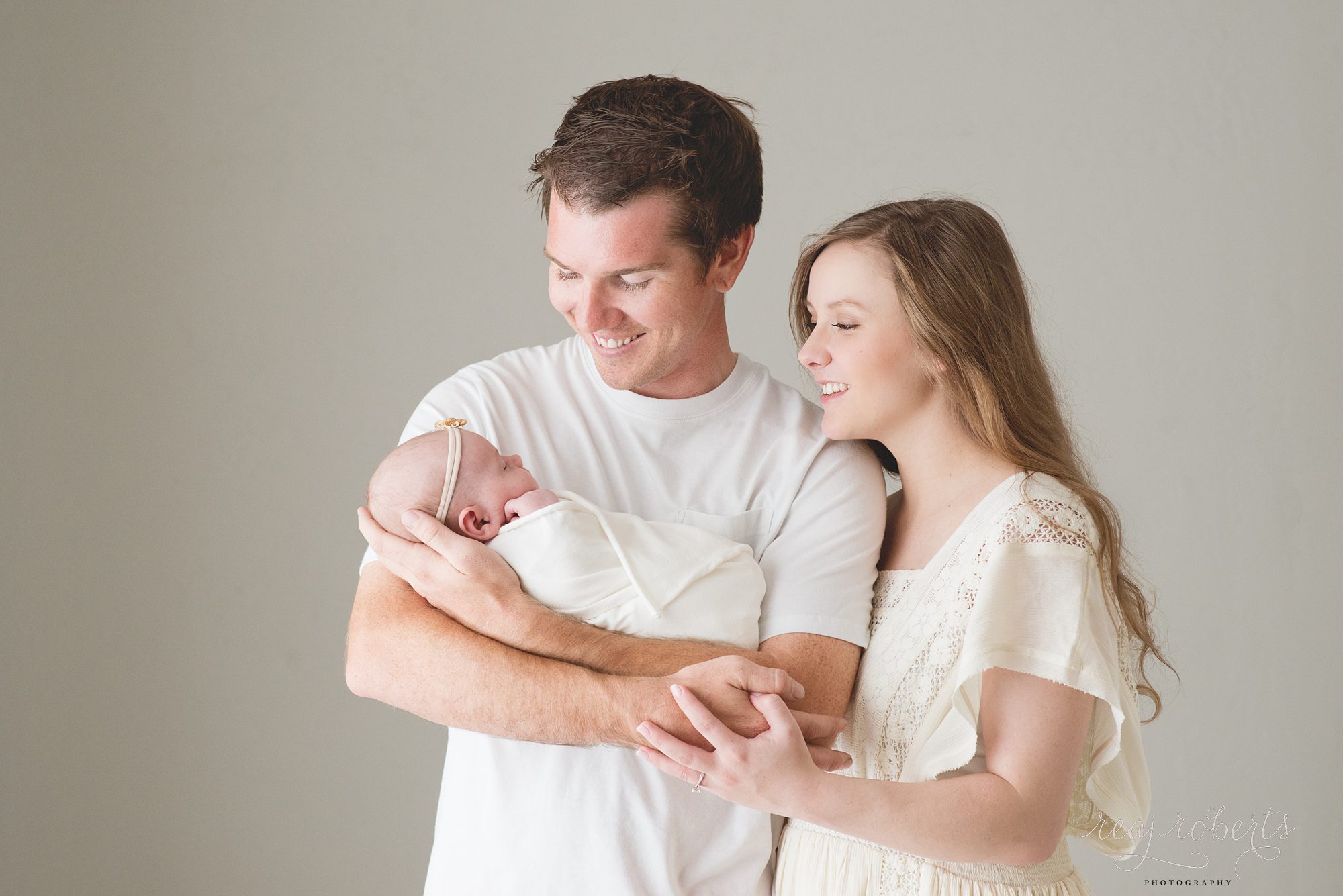 Smiling happy family holding newborn | Reaj Roberts Photography
