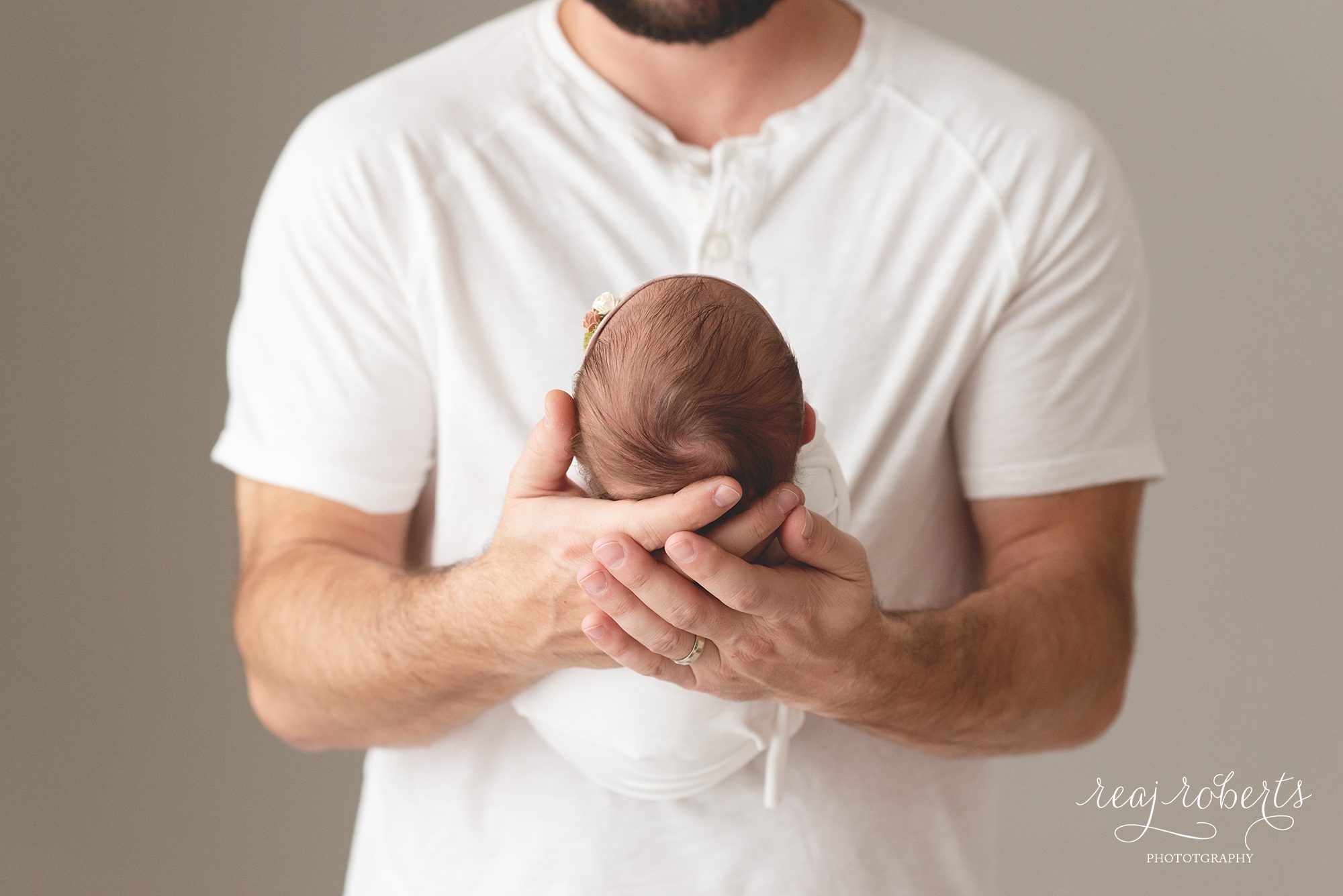 newborn baby held in father's hands | Reaj Roberts Photography