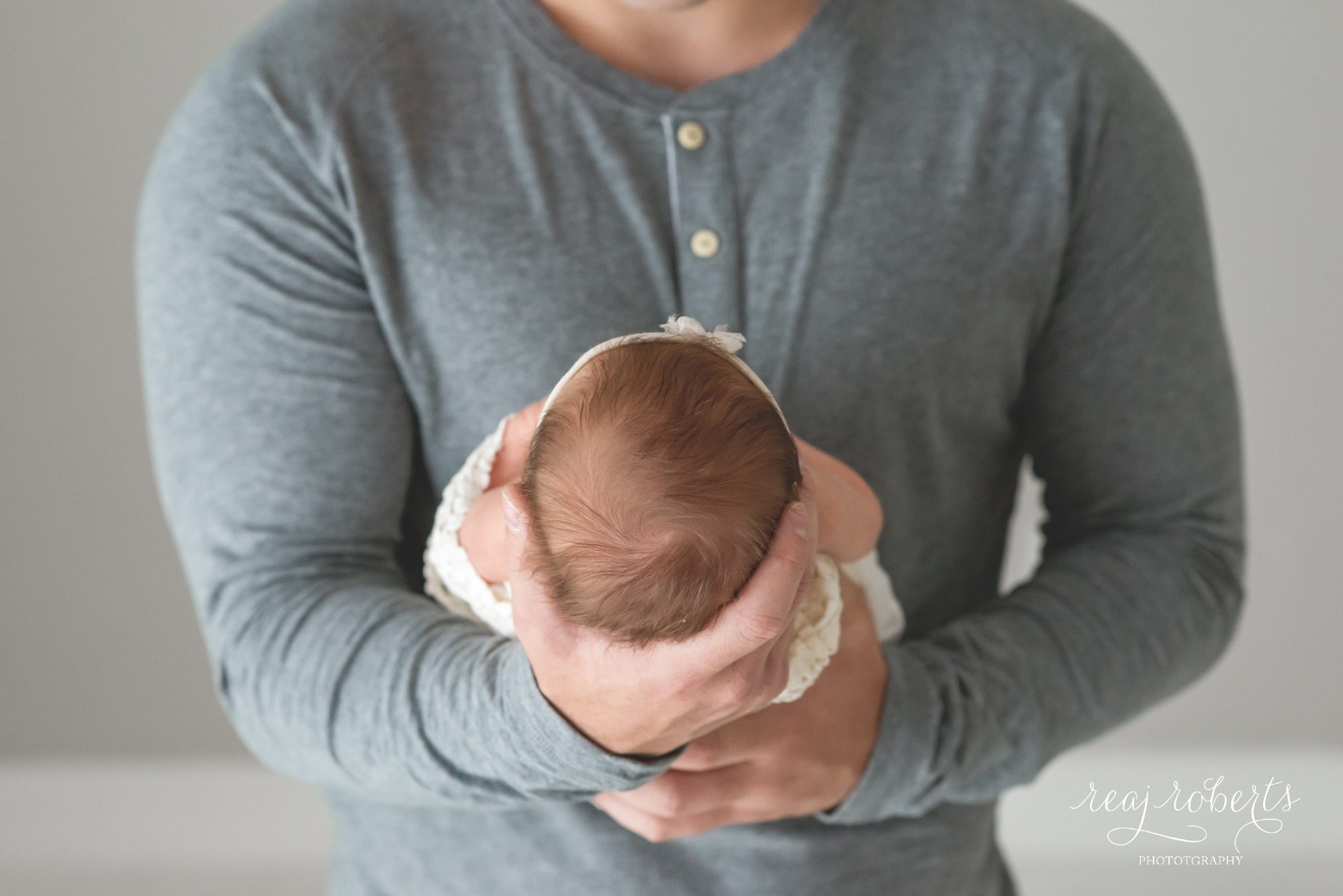 newborn held in dad's hands | Reaj Roberts Photography