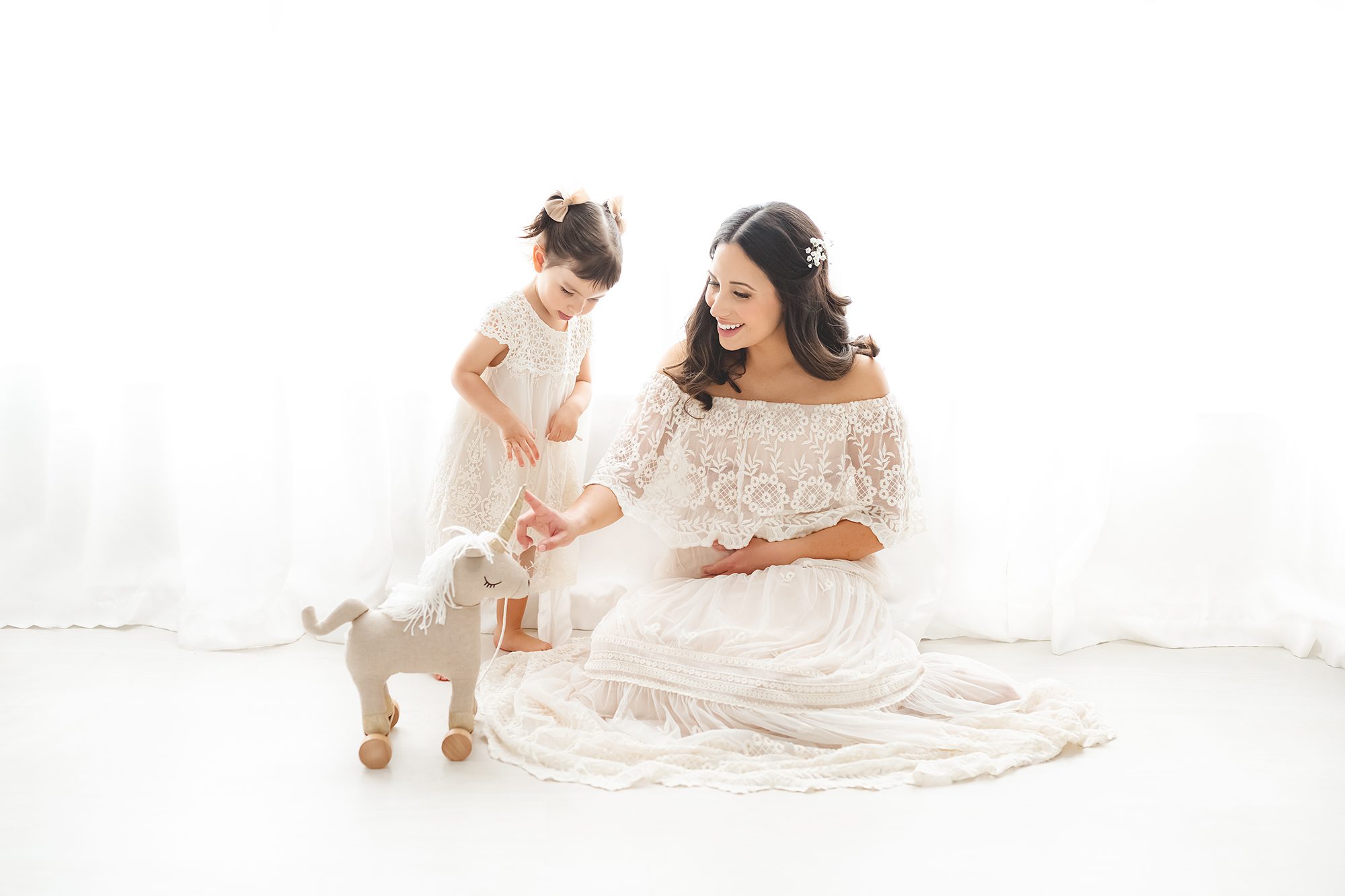 Pregnant mother sitting with daughter playing. Phoenix luxury pregnancy photos by Reaj Roberts Photography