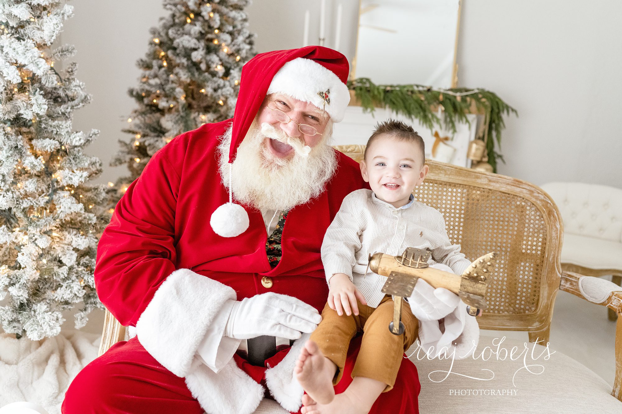© Reaj Roberts Photography Chandler Arizona Photos with Santa | boy sitting on Santa's lap with gold airplane