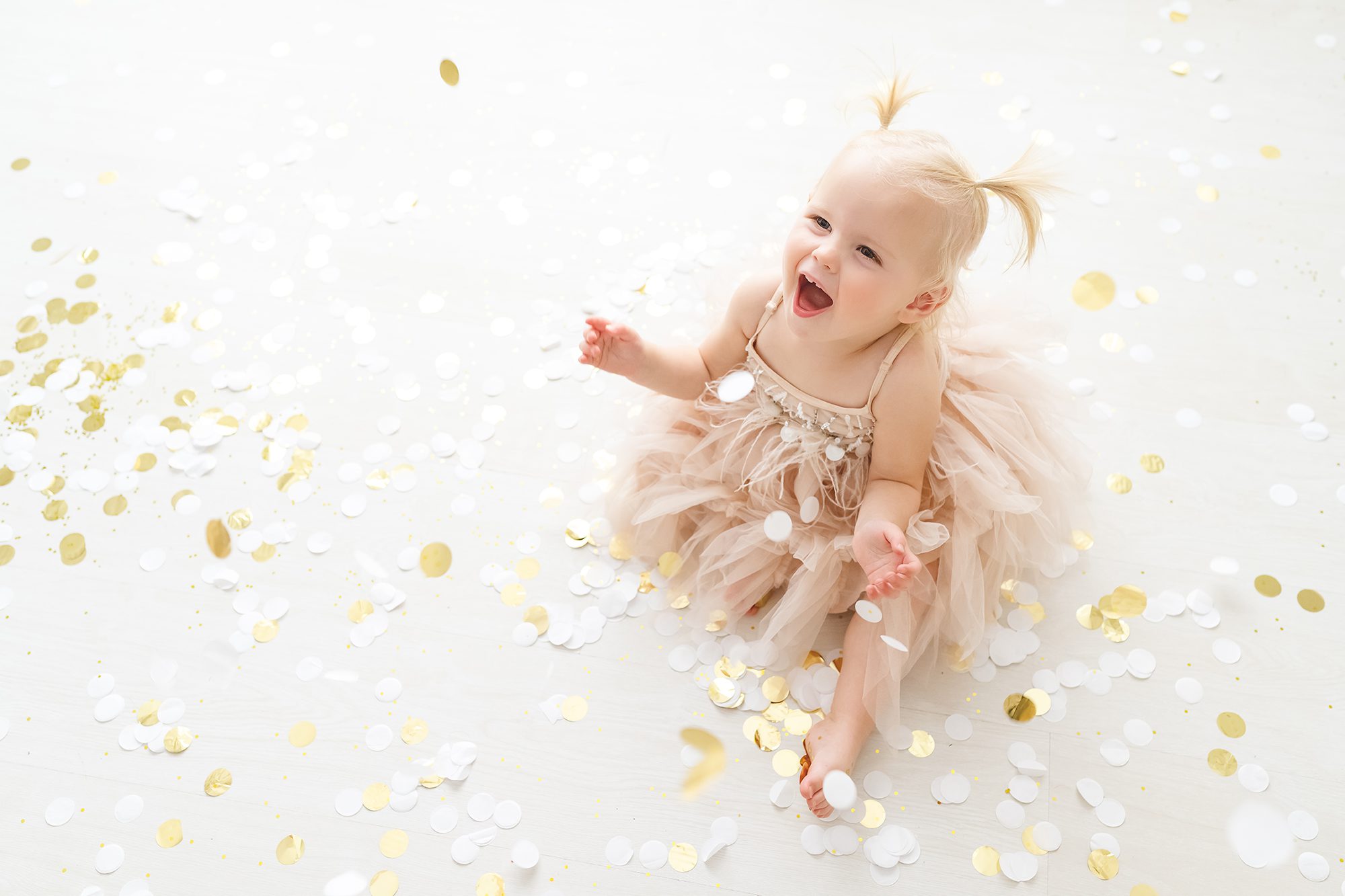 new years eve photoshoot ideas for kids.  Baby girl in blush pink dress with gold confetti smiling and laughing.